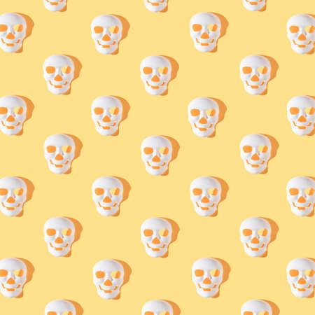 Halloween skeleton masks with sunshine shadows on bright yellow background. Minimal autumn holiday pattern.の写真素材