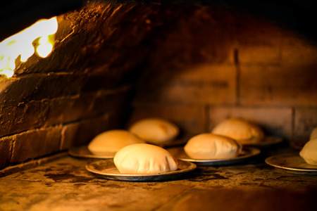 Stone wood oven with fire baking fresh homemade breadの写真素材