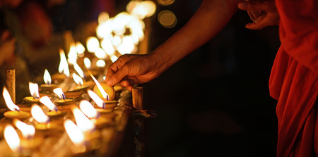 Buddhist monk hands lighting candle lighting candle in dark ,Chiang mai , Thailandの写真素材