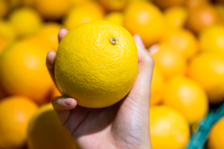 Female Hand pick up Orange in marketの写真素材