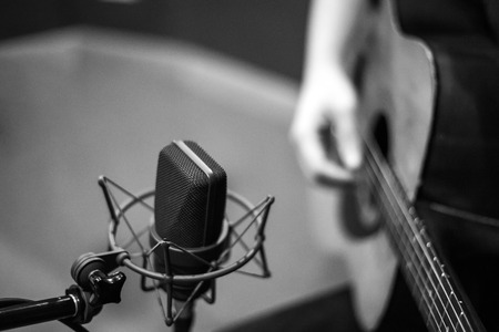 selective focus microphone and blur Man playing guitar backgroundの写真素材