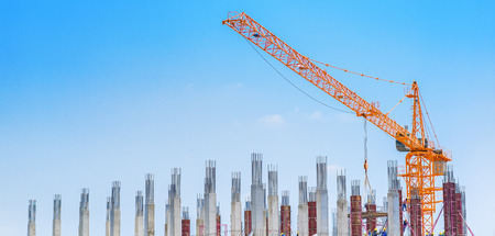 Crane and building construction site against blue skyの写真素材
