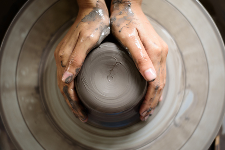 woman potter hands makes on the pottery wheel clay potの写真素材