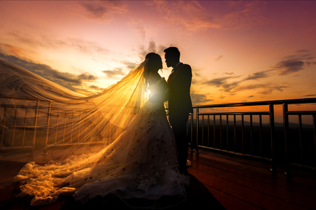 silhouette of wedding Couple in love kissing and holding hand together during sunset with evening sky backgroundの写真素材