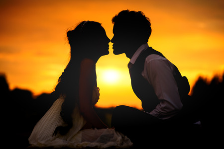 silhouette of wedding Couple in love kissing and holding hand together during sunset with evening sky backgroundの写真素材