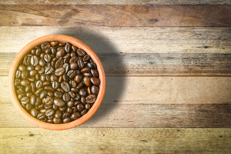 top view of roast Coffee Beans in a cup on wooden table backgroundの写真素材