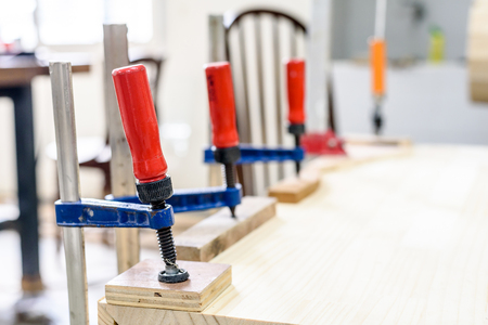Clamped pieces of wood with c-clamps and bar clamp , wooden parts in the carpentry workshopの写真素材