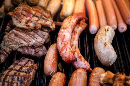 Closeup of mixed grilled sausages and barbecue steak on the grillの写真素材