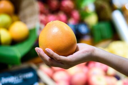 Female Hand holding selected Orange in fruits marketの写真素材