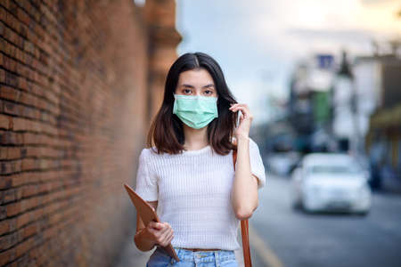 young  beautiful asian woman showing how to wear a medical mask or  showing how to correctly wear hygiene surgical mask step by step on white backgroundの写真素材