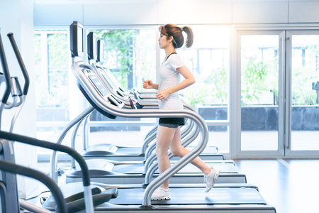 Asian girl running exercising on treadmill at sport gym , woman fitness workout.