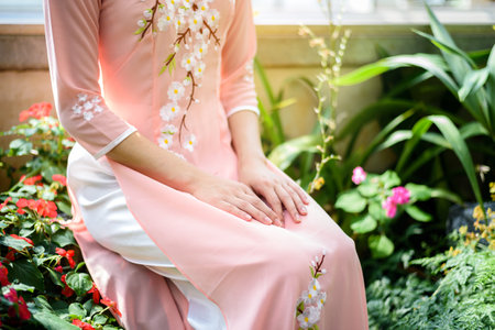 Portrait of Asian girls with Ao-Dai Vietnam traditional dress costume  sitting in flower gardenの写真素材