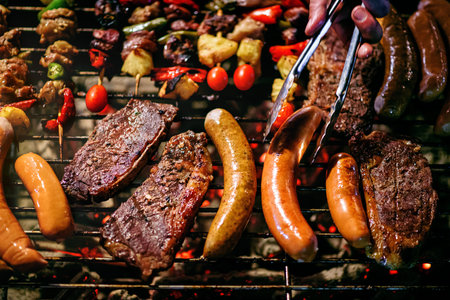 chef grilling steaks with grilled sausages and  skewers barbecue