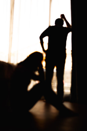 blur of Silhouettes of difficult relationship couple quarreling in dark bedroom at sunset , Stay at home quarantine coronavirus pandemic preventionの写真素材