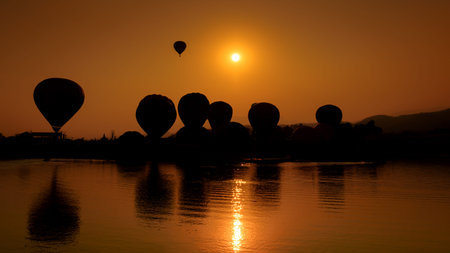 Silhouette hot air balloon over mountains in sunset skyの写真素材