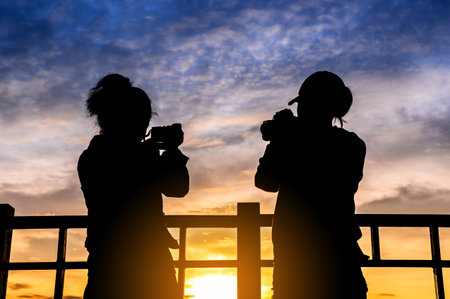 silhouette of two woman taking picture with camera at sunrise on DOI SUTHEP mountain viewpoint,...