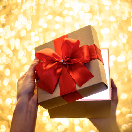 Woman hands opening a gift box wrapped with red ribbon on golden yellow bokeh lights background

christmas, new year, birthday conceptの写真素材