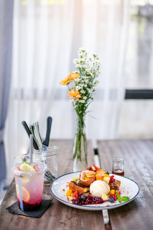 Beautiful breakfast or dessert French toast with Mixed fruit , ice cream , italian soda on wooden table. Modern bright white kitchen interiorの写真素材