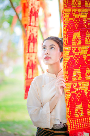 Beautiful smiling asian woman in traditional lanna style dress with colorful Lanna Tung flag, Chiang mai, Thailandの写真素材