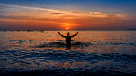 Silhouette of freedom Man Raising Hands in blue sea beach at sunsetの写真素材