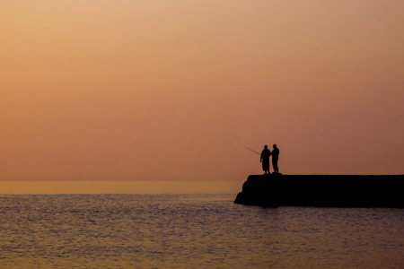 Silhouette of fishermen against the sky at sunriseの写真素材