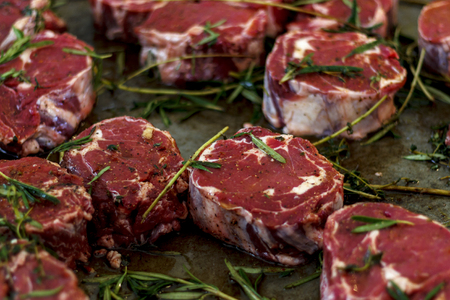 raw pieces of beef steak with rosemary sprigs in a frying panの写真素材