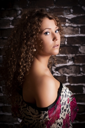 Beautiful young curly hair woman wearing sexy dress on brick wall background  Fashion portrait の写真素材