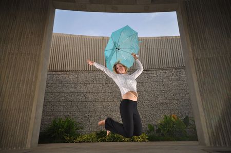 Caucasian Woman Dancing With Umbrella doing a jumpの写真素材