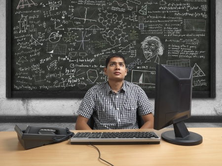 Asian Indian man thinking very hard in front of calculationsの写真素材
