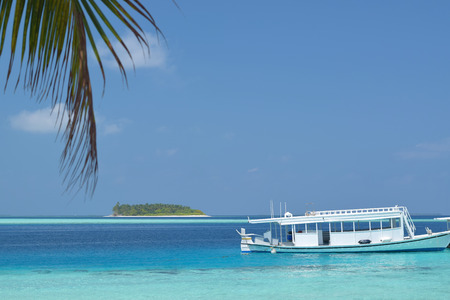 Calm scenic landscape of maldives showing passenger boat park in clear watersの写真素材