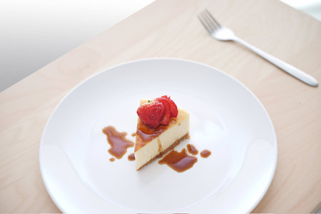close up of a small slice of cheese cake with strawberry toppings. Useful for food related themeの写真素材