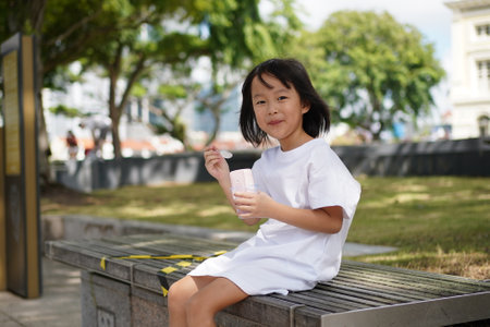 Asian chinese girl enjoying her cup of ice cream outdoorsの写真素材