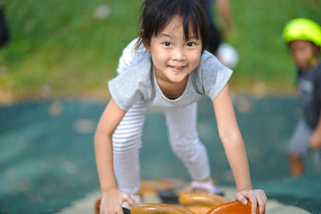 Confident asian chinese girl child smiling as she climbs rock wallの写真素材