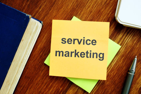 Writing note showing service marketing. The text is written on a small colored paper. The book, pen,...