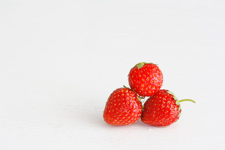 Strawberries with leaf on the white wooden background