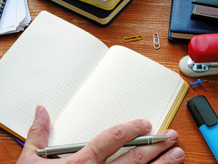 Men's hand writing in a blank notebook sheet, home office lifestyle workspace, mock up with copy space.の写真素材