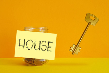 Concept of housing loan, finances and savings for home. Mortgage and taxes concept. A jar with coins and the inscription houseの写真素材
