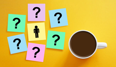 Seeking answers or solutions to problems are shown by picture of man standing in front of a bunch of questionsの写真素材