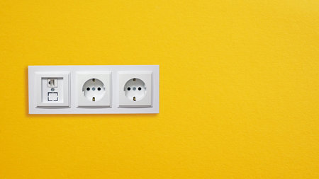 Modern White Power Outlets and Internet Socket on orange wall background with copy space. Minimalist Interior with Power and Data Accessの写真素材