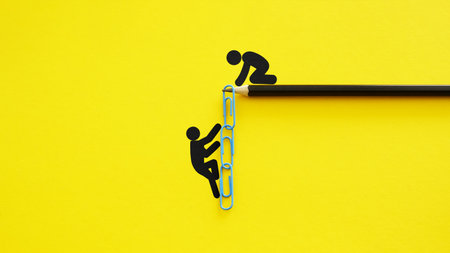 Mentorship and support metaphor with paperclip chain ladder on yellow background, teamwork and guidance conceptの写真素材