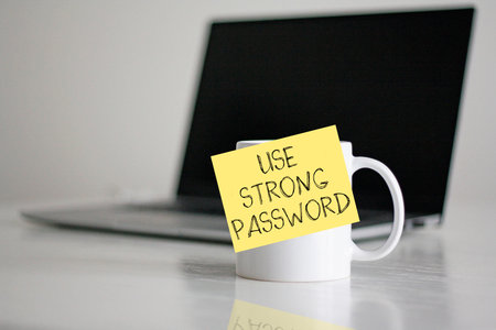 Strong Password Security Concept - Use Strong Password Note on Coffee Mug with Laptop. Cybersecurity and Data Protection Awareness.の写真素材