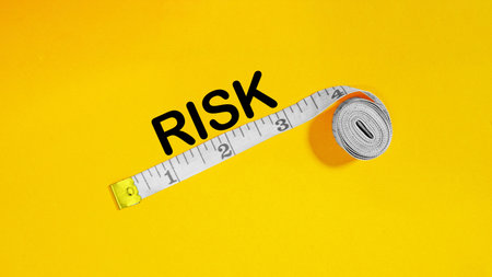 Risk Analysis and Management Concept - Measuring and Assessing Risk Level with Tape Measure on Yellow Backgroundの写真素材