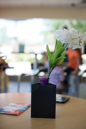 Black space for your text Menu frame on table with Restaurant Cafe Shop Interior Background. Mobile, newspaper and white flowers decoration on the table with bright blurred background. business mmeting.の写真素材