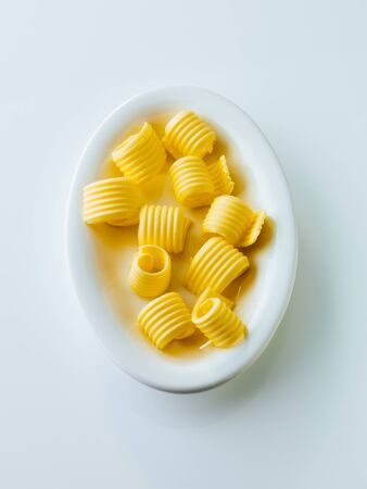 Butter curl or roll on a plate isolated on white backgroundの写真素材