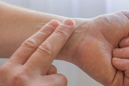 Close-up of a person checking pulse on the wrist using fingers. Concept of health monitoring, heart...