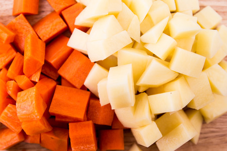 Diced carrots & diced potatoes on a cutting boardの写真素材