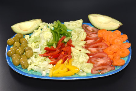 vegetable salad with olives and tomatoes on a blue plateの写真素材
