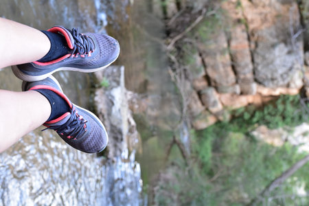 Female legs in sneakers on the background of a waterfall. Close-up.の写真素材