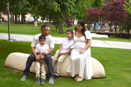 Portrait of a happy family sitting on a bench in the parkの写真素材