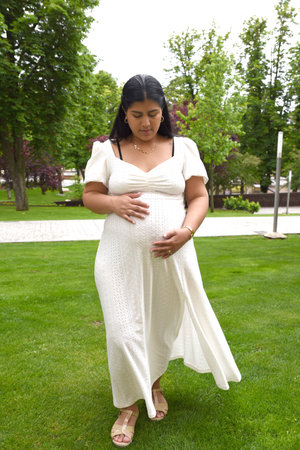 Pregnant woman in white dress in the park on a sunny dayの写真素材
